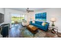 Bright living room with a blue sofa, wood floors, and sliding doors to the outside at 6141 Bahia Del Mar Blvd # 129, St Petersburg, FL 33715