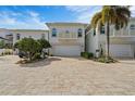 Elegant two-story home featuring a well-manicured lawn and a spacious brick driveway leading to a two-car garage at 830 Pinellas Bayway S, St Petersburg, FL 33715