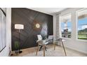 Stylish home office with a dark accent wall, modern desk, and bright windows offering scenic views of the outdoors at 10589 Farm Hill Ave, Land O Lakes, FL 34638