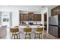 Modern kitchen featuring a large island with seating, stainless steel appliances, and elegant dark wood cabinetry at 10589 Farm Hill Ave, Land O Lakes, FL 34638