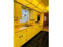 This kitchen features yellow cabinetry, black tile flooring, and a unique ceiling at 1220 57Th N St # 204C, St Petersburg, FL 33710