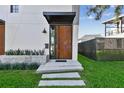 A close-up view of the minimalist front door with unique metal material and xeriscape landscaping at 1312 W Azeele St # 2, Tampa, FL 33606