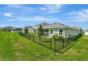 Well-maintained backyard with green lawn and black metal fence; perfect outdoor space at 16633 Mooner Plank Cir, Wimauma, FL 33598