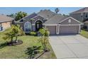 Inviting single-Gathering home showcasing lush landscaping and a spacious driveway at 2310 Wood Pointe Dr, Holiday, FL 34691