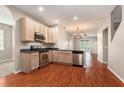 Bright kitchen featuring stainless steel appliances, light wood cabinetry, and elegant laminate flooring at 3219 Gianna Way, Land O Lakes, FL 34638