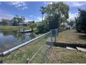 Scenic backyard with a pond view and private dock area, enhanced by lush landscaping and a secure fence at 3542 Delta Pl, Holiday, FL 34691