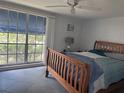 Sunlit bedroom featuring a wooden bed frame, ceiling fan, and large window with serene outdoor views at 3542 Delta Pl, Holiday, FL 34691
