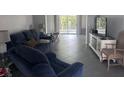 Bright living room with a comfortable blue sofa, tile flooring, and a sliding glass door leading to the outside at 3542 Delta Pl, Holiday, FL 34691