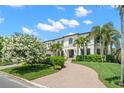 Elegant home featuring a lush front lawn, a brick driveway, and meticulously landscaped gardens at 5025 W Homer Ave, Tampa, FL 33629