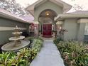 Inviting front entrance with a water fountain, lush garden, and a striking red double-door entry at 6805 Monet Cir, Temple Terrace, FL 33617