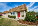Charming single-story home featuring a red front door, manicured landscaping, and a well-maintained lawn at 6935 Monte Carlo N, Pinellas Park, FL 33781