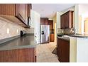 Well-lit kitchen featuring stainless steel appliances, wood cabinetry, and tile backsplash at 8341 Shallow Creek Ct, New Port Richey, FL 34653