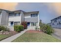 Charming condo with lush landscaping, light gray paint, blue doors, and walkway at 14800 Walsingham Rd # 301, Largo, FL 33774