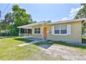 View of home showcasing a covered porch, orange front door, and verdant lawn at 1601 24Th S St, St Petersburg, FL 33712