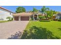 Charming home featuring a brick driveway, lush lawn, mature palm trees, and a three-car garage at 1819 Bella Casa Ct, Tampa, FL 33618