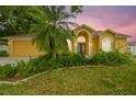 Charming yellow home with a well-manicured lawn, lush landscaping and double door entry at 23211 Lucerne Pl, Land O Lakes, FL 34639
