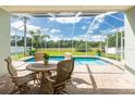 Screened pool area featuring a clear blue pool, outdoor seating, and a view of the green landscape at 4007 Canter Ct, Valrico, FL 33596