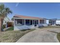 Charming single-story home with a screened porch and well-lit exterior, surrounded by a lush lawn and mature trees at 440 S Bayshore Dr, Madeira Beach, FL 33708