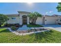 Charming single-story home featuring a well-manicured lawn, mature landscaping, and a three-car garage at 4693 Aylesford Dr, Palm Harbor, FL 34685
