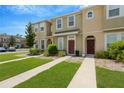 View of townhome exteriors with landscaped lawns and sidewalks, under a clear blue sky at 7029 White Treetop Pl, Riverview, FL 33578