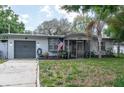 Inviting single-story home featuring a screened-in porch, a garage, and a well-manicured front yard at 809 S Palm Dr, Largo, FL 33770