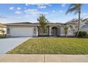 Inviting single-story home with a lush green lawn, attached garage, and covered front entryway at 8818 Poe Dr, Hudson, FL 34667