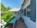 Inviting front porch with a wooden bench and decorative plants, leading to a white front door and blue shutters at 12202 Meadowbrook Ln, Hudson, FL 34667