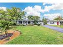 Charming single-story home with well-maintained lawn and mature landscaping, driveway, and a green metal roof at 1572 84Th N Ave, St Petersburg, FL 33702