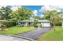 Charming single-story home with well-maintained lawn and mature landscaping, a green metal roof, and a driveway at 1572 84Th N Ave, St Petersburg, FL 33702