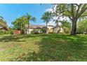 Single-story home with lush front lawn and mature trees offering shade and curb appeal on a sunny day at 1591 Chestnut W Ct, Palm Harbor, FL 34683