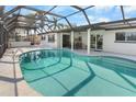 A beautiful screened-in pool with clear water, a covered lanai, and palm trees in the background at 200 98Th Ne Ave, St Petersburg, FL 33702
