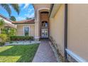 An arched entryway leading to elegant double doors, complemented by lush landscaping at 2630 Grand Lakeside Dr, Palm Harbor, FL 34684