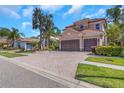 Inviting two-story home featuring a tile roof, manicured landscaping, and a spacious brick driveway at 2630 Grand Lakeside Dr, Palm Harbor, FL 34684