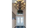 Grand foyer featuring a high ceiling, a decorative chandelier, and elegant glass double doors at 2630 Grand Lakeside Dr, Palm Harbor, FL 34684