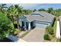 Beautiful single-story home featuring a paver driveway, an attached two-car garage, and lush tropical landscaping at 5239 Admiral Pointe Dr, Apollo Beach, FL 33572