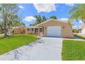 Inviting single-story house featuring a lush green lawn, attached garage, and neutral paint scheme at 7336 Cherry Laurel Dr, Port Richey, FL 34668