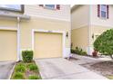 Close-up of the townhome featuring a one-car garage, front yard landscaping, and a well-lit entrance at 10822 Verawood Dr, Riverview, FL 33579