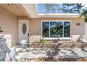 Close-up of the home's front entrance, featuring a white door with decorative window and well-maintained landscaping at 1250 12Th Sw Ct, Largo, FL 33770