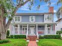 Charming two-story home featuring a welcoming front porch with swing, manicured lawn, and brick walkway at 1403 W Watrous Ave, Tampa, FL 33606