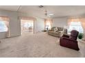 Spacious living room featuring neutral carpeting, comfortable seating, and abundant natural light from the large windows at 34150 Estates Ln, Wesley Chapel, FL 33543