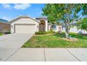 Charming home with a well-kept lawn, mature tree, and a two-car attached garage at 4247 Balmoral Ct, Wesley Chapel, FL 33543