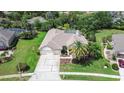 An aerial view showing the home's layout, landscaping, large driveway, and proximity to surrounding greenery at 5460 Millbrook Way, Palm Harbor, FL 34685