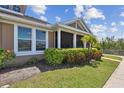 Well-maintained home exterior with lush landscaping, healthy green grass, and a private screened-in porch at 5702 Tides Pl, Apollo Beach, FL 33572