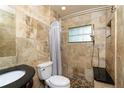 Bathroom features a tiled shower, a dark vanity, and neutral-toned tile walls at 6801 5Th N St, St Petersburg, FL 33702