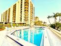 Outdoor swimming pool surrounded by lounge chairs at a condo building with beautiful landscaping at 690 Island Way # 707, Clearwater Beach, FL 33767