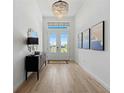 Bright foyer with light wood floors, a decorative mirror, and a contemporary light fixture at 8118 Thruso Rd, Port Charlotte, FL 33981