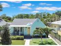 Charming single-story home featuring a cozy front porch, light teal siding and manicured lawn at 136 30Th N Ave, St Petersburg, FL 33704