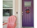 Up close view of a purple front door with a ladybug wreath and coral Adirondack chair at 1614 E Nome St, Tampa, FL 33604