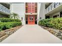 Building entrance featuring a stone walkway, red double doors, and lush landscaping, creating a welcoming entry at 2612 Pearce Dr # 209, Clearwater, FL 33764