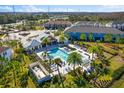 Aerial view of a sparkling community pool, cabana, and lounge chairs surrounded by tropical greenery at 3214 Painted Blossom Ct, Lutz, FL 33558